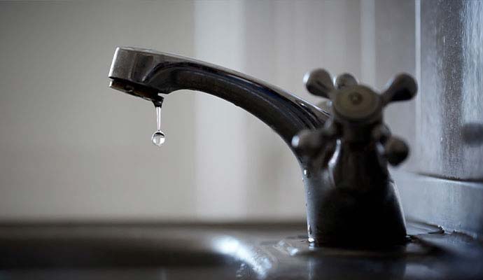 A water droplet falling from leaky faucet tap
