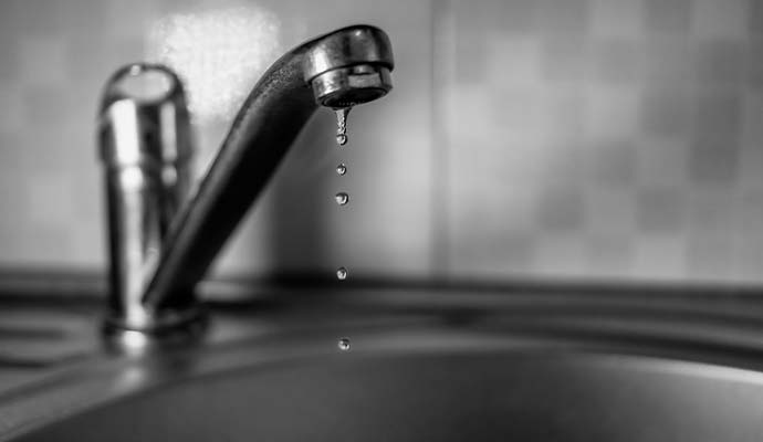 A water droplet falling from leaky faucet tap
