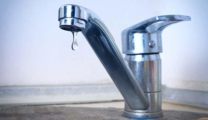 A water droplet falling from leaky faucet tap