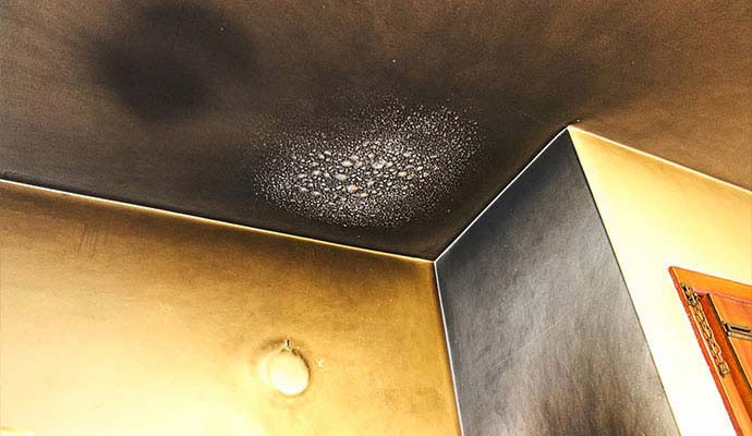 Black soot residue and blistered paint on ceiling corner