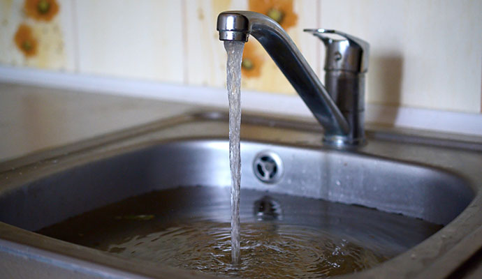 Stainless steel kitchen sink filled with dirty water