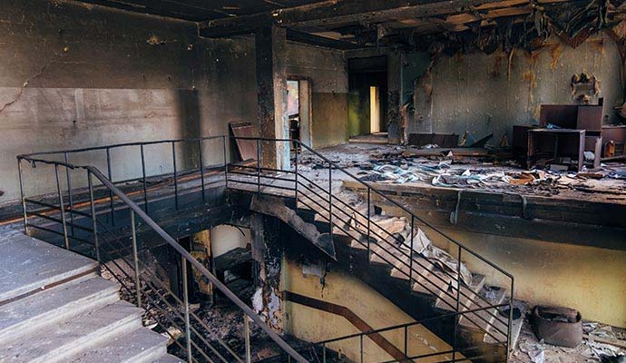 Fire damaged building interior with charred staircase and debris