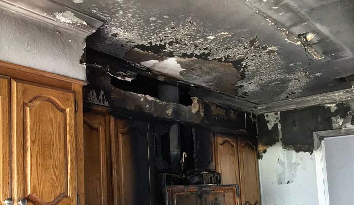 Fire damaged kitchen ceiling and cabinets with charred hole