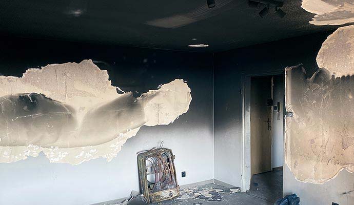 Heavy black soot and smoke damage on room walls and ceiling