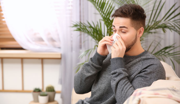 Man sneezing with tissue from smoke odor irritation