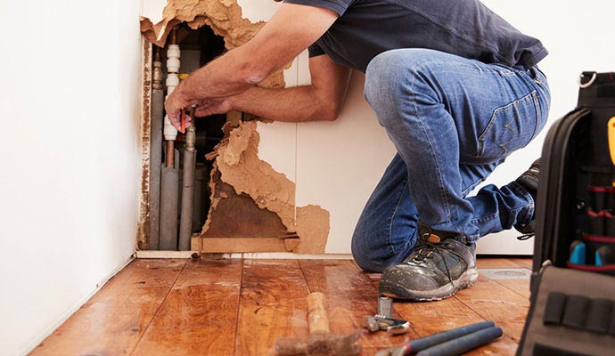Plumber repairing hidden wall pipe leak