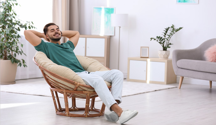 Smiling man reclining comfortably in a round papasan chair