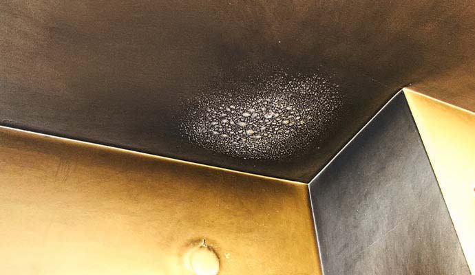Black soot residue and blistered paint on ceiling corner
