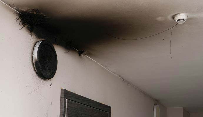 Black soot residue and smoke stains on wall and ceiling