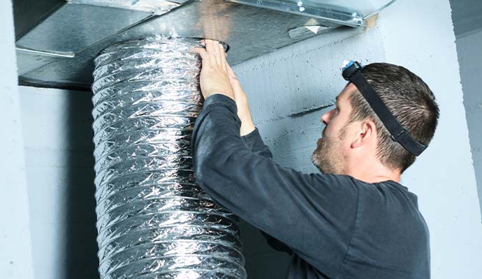 Technician inspecting flexible aluminum air duct pipe