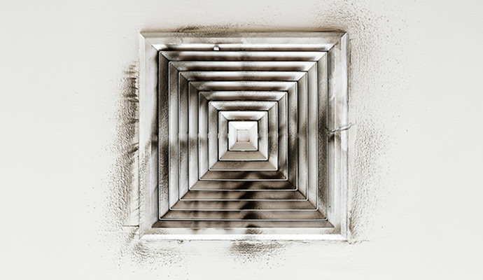 Black soot and smoke residue around a ceiling air vent