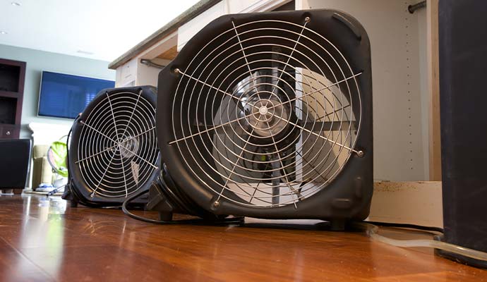 Commercial air movers drying interior floor and cabinets