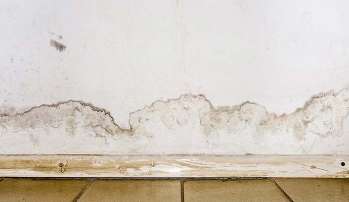 Water damaged drywall with moisture stains above floor