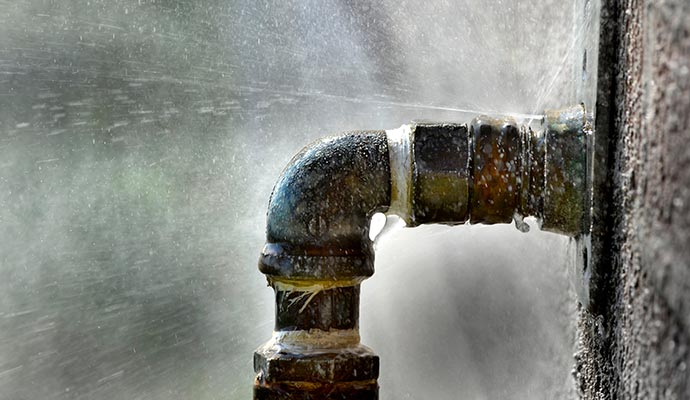 Water spraying from a leaking metal pipe elbow joint